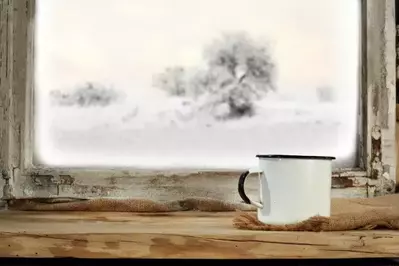 White mug on window sill looking out onto winter snow