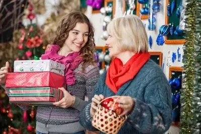 Beautiful mother and daughter with bauble basket and presents in Christmas store