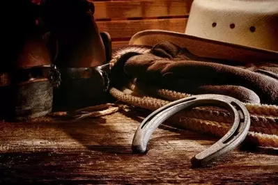Western horse riding kit with cowboy boots, hat, lasso, and horse shoe