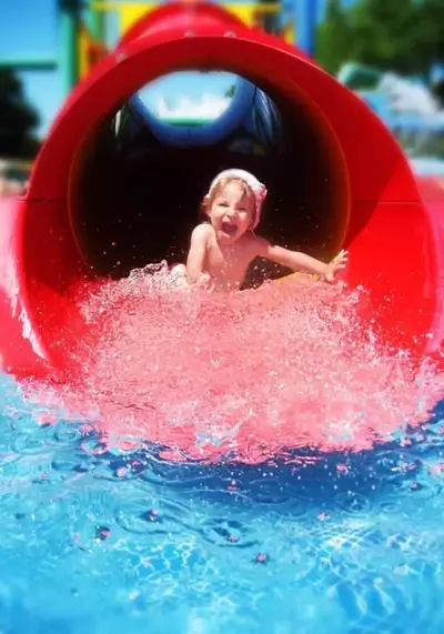 Little girl going down red water slide