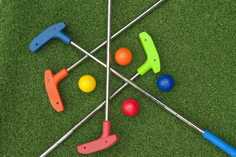 mini golf clubs and balls laying flat on a putting green